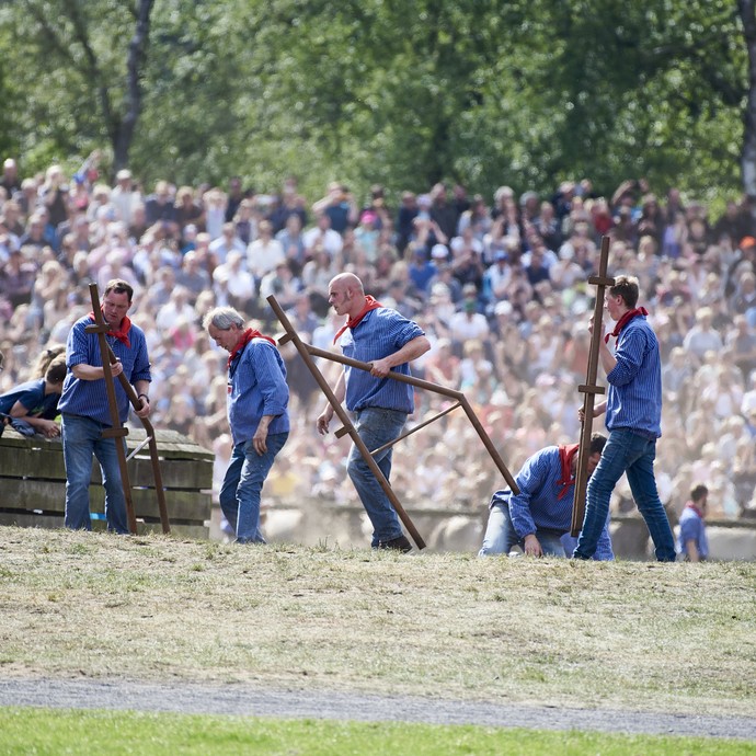 Mitarbeiter der Wildpferdebahn räumen Teile einer Absperrung fort. Sie tragen weiß-blau gestreifte Hemden und rote Halstücher. (vergrößerte Bildansicht wird geöffnet)